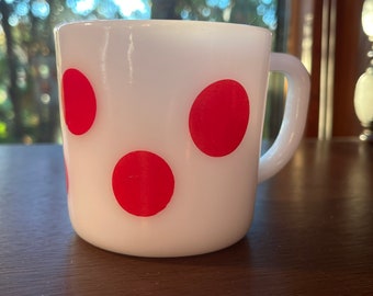 May include: White ceramic mug with three red polka dots.