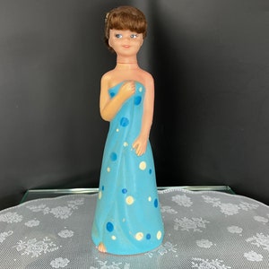 Puede incluir: Una muñeca de lunares azules y blancos con una toalla. La muñeca tiene el pelo castaño y los ojos azules.