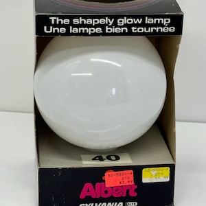 May include: A white, round light bulb in a cardboard box with the brand name "Albert" and the text "The shapely glow lamp" and "Une lampe bien tournée". The box also has a price tag that says "£3.49".