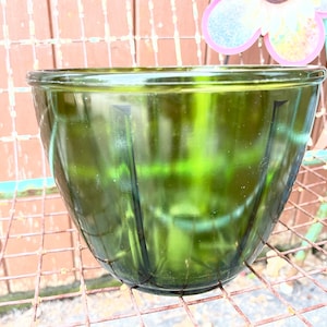 Pode incluir: Uma tigela de mistura de vidro verde escuro grande com um design canelado. A tigela está sentada em uma grade de arame de metal.