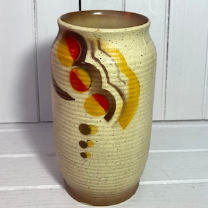 May include: A white ceramic vase with a speckled finish and abstract brown, yellow, and red painted designs.