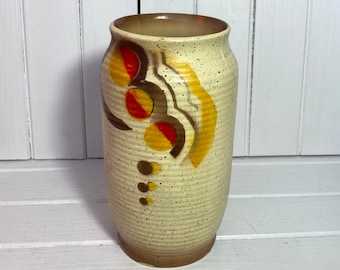 May include: A white ceramic vase with a speckled finish and abstract brown, yellow, and red painted designs.