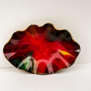 Könnte beinhalten: Eine dekorative Glasschale mit einem leuchtenden roten und schwarzen Innenraum. Die Schale hat eine wellenförmige, blütenblattartige Form mit einem goldfarbenen Rand. Die Farben verschmelzen zu einem einzigartigen, künstlerischen Design.