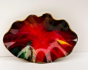 May include: A decorative, glass bowl with a vibrant red and black interior. The bowl has a wavy, petal-like shape with a gold-colored rim. The colors blend together, creating a unique, artistic design.