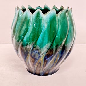 May include: A green and blue ceramic vase with a wavy, textured design. The vase has a wide opening and a rounded bottom.
