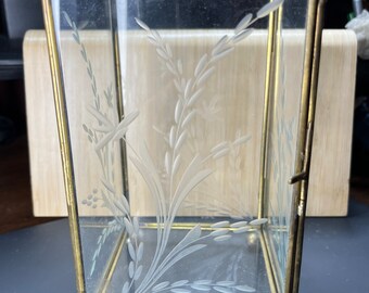 Könnte beinhalten: Eine transparente Glasvitrine mit einem goldenen Metallrahmen. Das Glas ist mit einem floralen Muster graviert. Die Vitrine hat eine Flügeltür und steht auf vier kleinen Füßen.