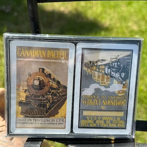 Puede incluir: Dos postales vintage con imágenes en blanco y negro de locomotoras de vapor. La postal superior presenta una locomotora de Canadian Pacific Railway con el texto "Canadian Pacific" e "Insist on travelling by C.P.R." La postal inferior presenta una locomotora de Dominion Express Company con el texto "Dominion Express Company of Canada" y "Send your Xmas & New Year parcels to your friends in Canada & U.S.A."
