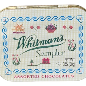 Könnte beinhalten: Vintage Whitman's Sampler Dose mit cremefarbenem Hintergrund und goldenem Rand. Die Dose hat ein dekoratives Muster mit blauen, roten und grünen Akzenten. Der Text "Whitman's Sampler" ist in grüner Schrift geschrieben. Nettogewicht: 50g.