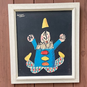 May include: A framed black and white illustration of a clown with a yellow hat, blue shirt, and red and white pants. The illustration is signed "Herbert Leupin".