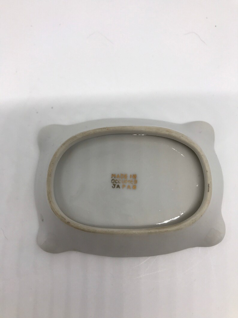 May include: White ceramic dish with a scalloped edge. The bottom of the dish has the text "Made in Occupied Japan" printed in gold.