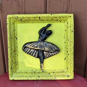 Peut inclure: Une figurine de ballerine noire et dorée dans un cadre vert avec des taches noires. Le cadre est en bois et a un aspect vieilli.
