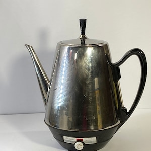 May include: A silver electric coffee percolator with a black handle and a black knob on the lid. The percolator has a black base with a control knob and the text "Sunbeam" and "Keep Hot Automatic".