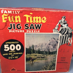 Könnte beinhalten: Eine rote Schachtel mit einem Bild eines Bergsees und einem Fischer auf der Vorderseite. Die Schachtel ist für ein 500-teiliges Puzzle namens "Fun Time" und trägt den Text "Fishing in the Rockies".