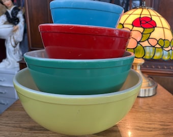 May include: A set of four nesting mixing bowls in yellow, green, red, and blue. The bowls are stacked on top of each other.