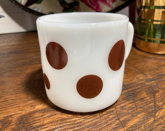 May include: White ceramic mug with a brown polka dot pattern.