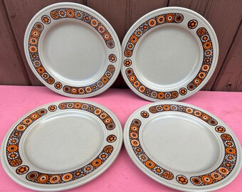 May include: Set of four beige ceramic dinner plates with a brown and orange geometric pattern around the rim.