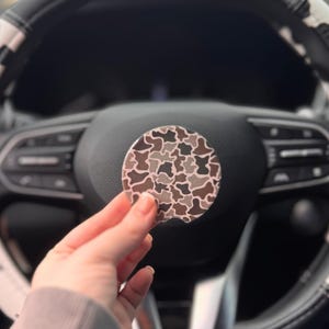 May include: A set of three ceramic mugs with a speckled, matte finish. The mugs are in shades of cream, light gray, and dark gray. Each mug has a simple, minimalist design and a rounded handle. The mugs are stacked on top of each other.