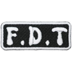 May include: Black rectangular patch with white embroidered text "F.D.T." outlined in white. The patch has a black background and a white border. The letters are in a playful, rounded font.
