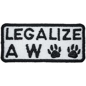Könnte beinhalten: Ein rechteckiger bestickter Aufnäher mit weißem Hintergrund und einem dicken schwarzen Rand. Der Text "LEGALIZE A W" ist in fetten schwarzen Großbuchstaben gestickt, gefolgt von zwei schwarzen Pfotenabdrücken auf der unteren Zeile.
