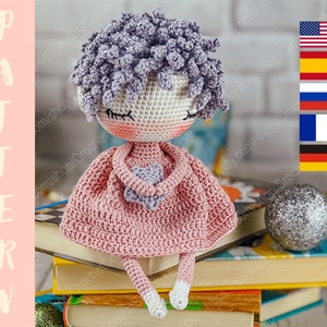 May include: Crocheted doll with purple hair, wearing a pink dress and holding a purple heart. The doll is sitting on a stack of books.
