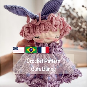 May include: A handmade crochet doll featuring long purple bunny ears, curly pink yarn hair, and a light purple dress with a polka dot pattern. The doll has embroidered closed eyes and pink cheeks. Text on the image reads: Crochet Pattern Cute Bunny.