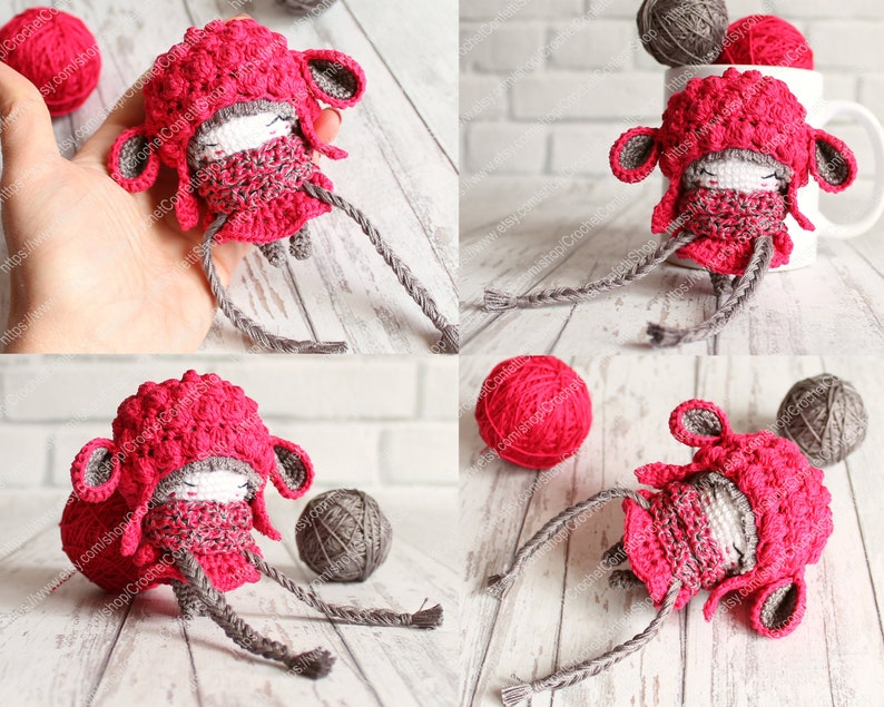 May include: A crocheted amigurumi doll wearing a pink hat and scarf. The doll has gray yarn for arms and legs. The doll is sitting on a white wooden surface.
