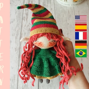 Peut inclure: Poup&eacute;e elfe en crochet avec des cheveux roux, une robe verte et un chapeau ray&eacute;. La poup&eacute;e tient un petit c&oelig;ur blanc.