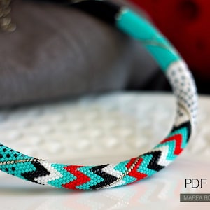 May include: A turquoise, white, black, and red beaded necklace with a geometric pattern. The necklace is on a white surface. PDF pattern MARFA ROMANOVSKAYA.