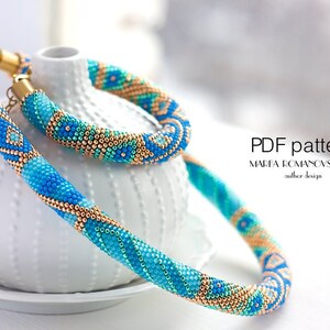 Puede incluir: Un conjunto de collar y pulsera de cuentas en tonos azules, turquesas y dorados. La joyería presenta patrones intrincados y se exhibe sobre un jarrón de cerámica blanco. La imagen incluye el texto "PDF pattern".