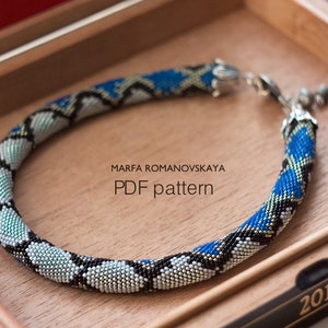 May include: A blue, black and silver beaded necklace with a silver clasp. The necklace is in a wooden box with the text "MARFA ROMANOVSKAYA PDF pattern" and "2011" on it.
