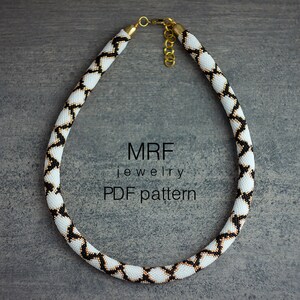 May include: A white, black and gold beaded necklace with a geometric pattern. The necklace is on a grey background. MRF jewellery PDF pattern.