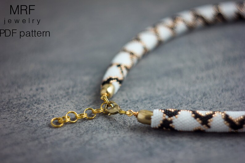 May include: A white and black beaded necklace with a gold clasp. The necklace is made with small beads in a geometric pattern.