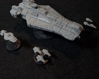 May include: A gray spaceship model with a long, pointed nose and a detailed design. The spaceship is on a black base and is surrounded by smaller gray spaceship models on black bases.