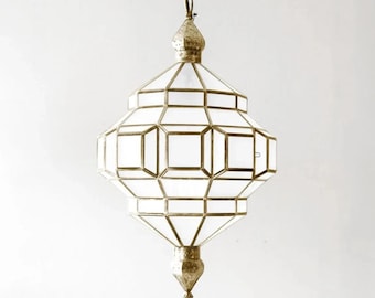 May include: A white geometric pendant light fixture with a gold metal frame. The light fixture has a pointed top and bottom and is suspended from a chain.