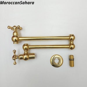 May include: Gold-toned kitchen faucet with a swivel spout and two handles. The faucet is shown disassembled with the parts laid out on a white surface.