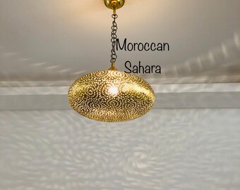 May include: A gold Moroccan Sahara pendant light with a delicate, intricate pattern. The light casts a beautiful pattern on the ceiling.