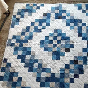A Peaceful Blue and Tan Geometric Quilt with a Center Array Surrounded by Sections of Blues and Tan Squares