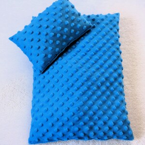 Könnte beinhalten: Ein hellblaues Babydecken- und Kissen-Set. Die Decke und das Kissen haben eine strukturierte, unebene Oberfläche. Das Set besteht aus einem weichen, plüschigen Material. Die Farbe ist ein leuchtendes, einfarbiges Blau.