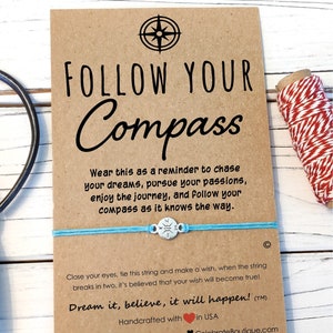 May include: A blue and silver compass charm bracelet with a brown card that reads "Follow Your Compass". The card also includes the text "Wear this as a reminder to chase your dreams, pursue your passions, enjoy the journey, and follow your compass as it knows the way."  The card also includes the text "Close your eyes, tie this string and make a wish, when the string breaks in two, it's believed that your wish will become true! Dream it, believe, it will happen! (TM)"