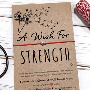 May include: A red string bracelet with a silver heart charm and a card that says "A Wish For STRENGTH" with a dandelion design. The card also includes the text "Close your eyes, tie this string and make a wish, when the string breaks in two. It's believed that your wish will become true! Dream it, believe, it will happen! (TM)" and "Handcrafted with in the UK".
