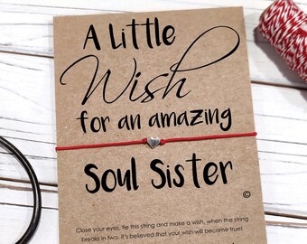 May include: A red string with a silver heart charm attached to a card that reads "A Little Wish for an Amazing Soul Sister". The card also includes instructions on how to make a wish and the text "Dream it, believe, it will happen!"