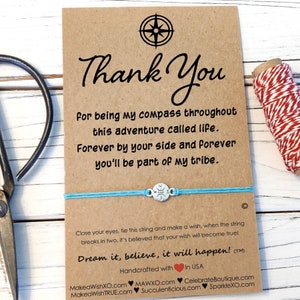 May include: A blue and silver friendship bracelet with a compass charm. The card reads "Thank You for being my compass throughout this adventure called life. Forever by your side and forever you'll be part of my tribe." It also says "Close your eyes, tie this string and make a wish, when the string breaks in two, it's believed that your wish will become true! Dream it, believe, it will happen!"