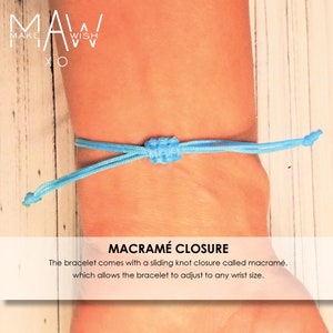 Pu&ograve; includere: Un braccialetto blu chiaro con chiusura a macram&egrave;. Il braccialetto &egrave; regolabile e ha una chiusura a nodo scorrevole. Il testo "MAW MAKE WISH XO" &egrave; visibile sullo sfondo.