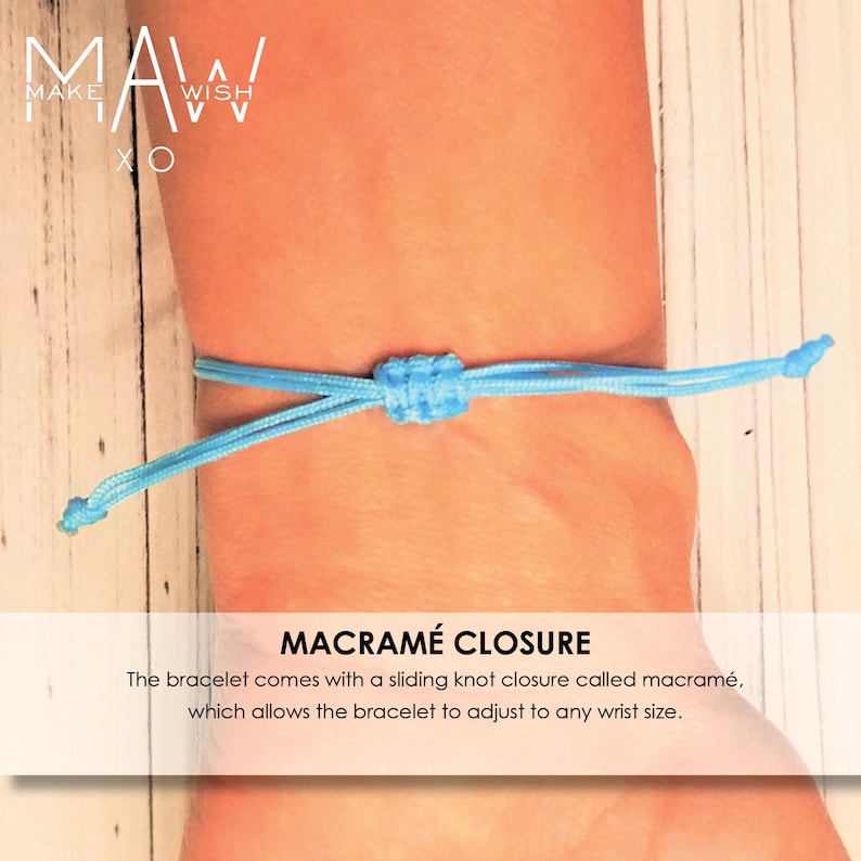 Pu&ograve; includere: Un braccialetto blu chiaro con chiusura a macram&egrave;. Il braccialetto &egrave; regolabile e ha una chiusura a nodo scorrevole. Il testo "MAW MAKE WISH XO" &egrave; visibile sullo sfondo.