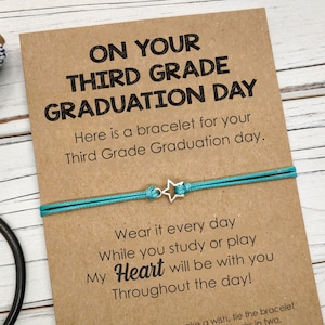 Puede incluir: Un brazalete de amistad azul turquesa con un dije de estrella plateada y una tarjeta que dice "On your third grade graduation day. Here is a bracelet for your third grade graduation day. Wear it every day while you study or play. My heart will be with you throughout the day!"