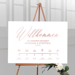 Könnte beinhalten: Weißes Hochzeitsschild mit roségoldener Schrift und einem Zeitplan der Ereignisse. Auf dem Schild steht "Willkommen" und die Namen Marjan & Steffen, mit dem Datum 19.05.2018. Das Schild wird auf einer Holzstaffelei präsentiert.