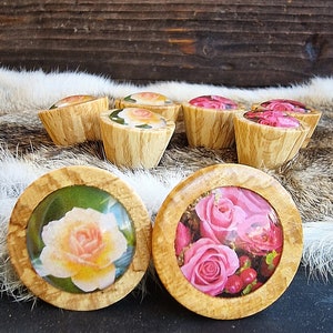 Könnte beinhalten: Sortiment an Holzknöpfen mit Blumendesigns. Die Knöpfe zeigen rosa, weiße und gelbe Rosen in verschiedenen Anordnungen. Die Knöpfe sind aus hellbraunem Holz mit natürlicher Maserung.