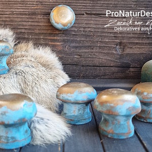 Könnte beinhalten: Sechs dekorative Knöpfe mit einer abgewetzten blauen und goldenen Oberfläche. Die Knöpfe sind aus Holz und haben einen rustikalen Look. ProNaturDesign: Zurück zur Natur Dekoratives aus Holz.