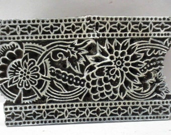 Pode incluir: Um bloco de impressão de madeira preto e branco com um design floral. O bloco tem um padrão detalhado de flores, folhas e videiras. É um bloco de impressão tradicional indiano usado para têxteis.