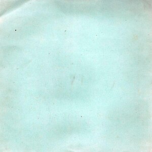 May include: A light blue, slightly textured paper background with minor imperfections. The paper has a faded appearance, with small dark spots and subtle streaks. The overall tone is muted and vintage.